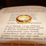 A photo of an open book with a gold ring laying on top of a page